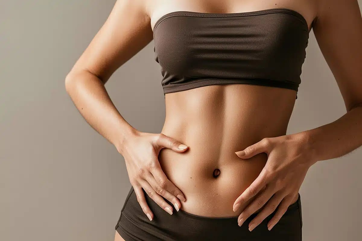 Woman touching stomach in studio with liposuction mockup Woman touching stomach in studio with liposuction mockup