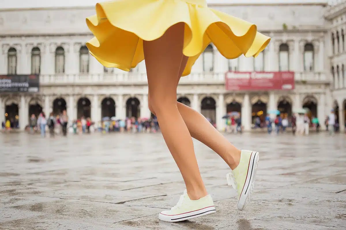 Cheerful young woman wearing sneakers and yellow skirt Cheerful young woman wearing sneakers and yellow skirt