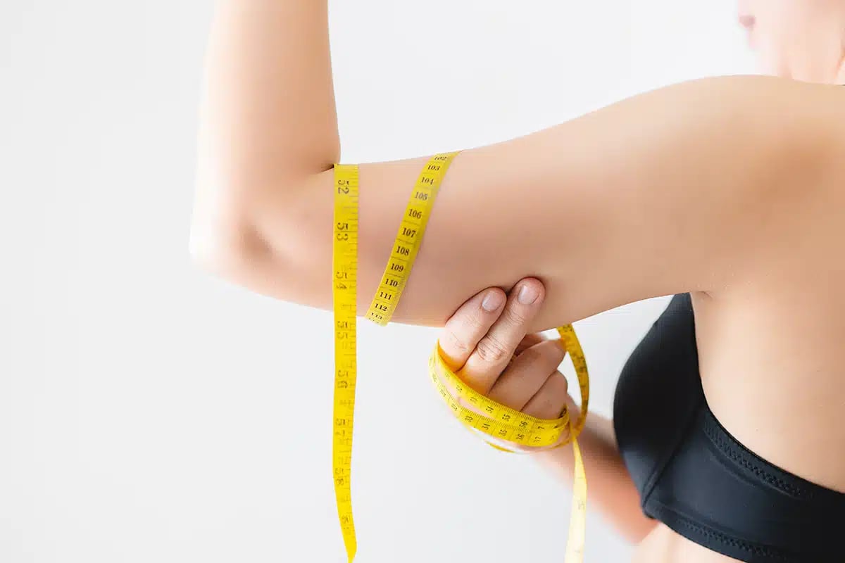 Close up of a woman grabbing upper arm with excess fat Close up of a woman grabbing upper arm with excess fat