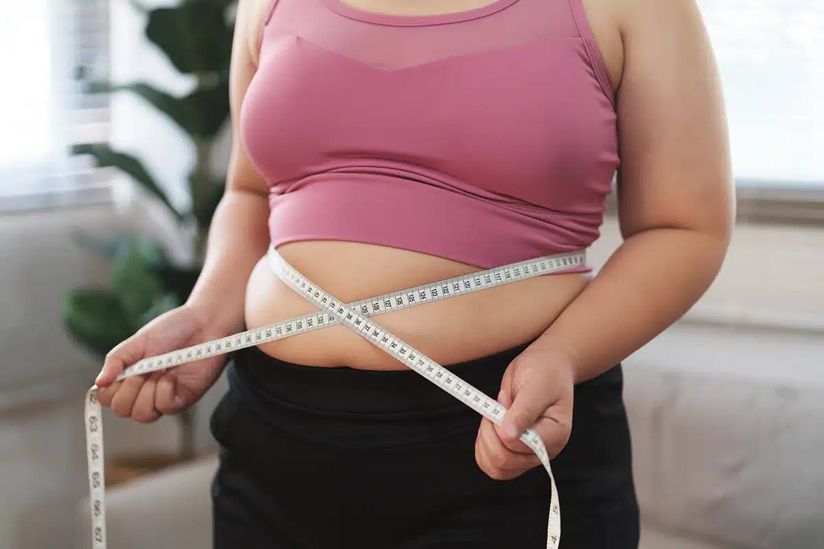 Woman measuring abdomen with tape for body contour evaluation