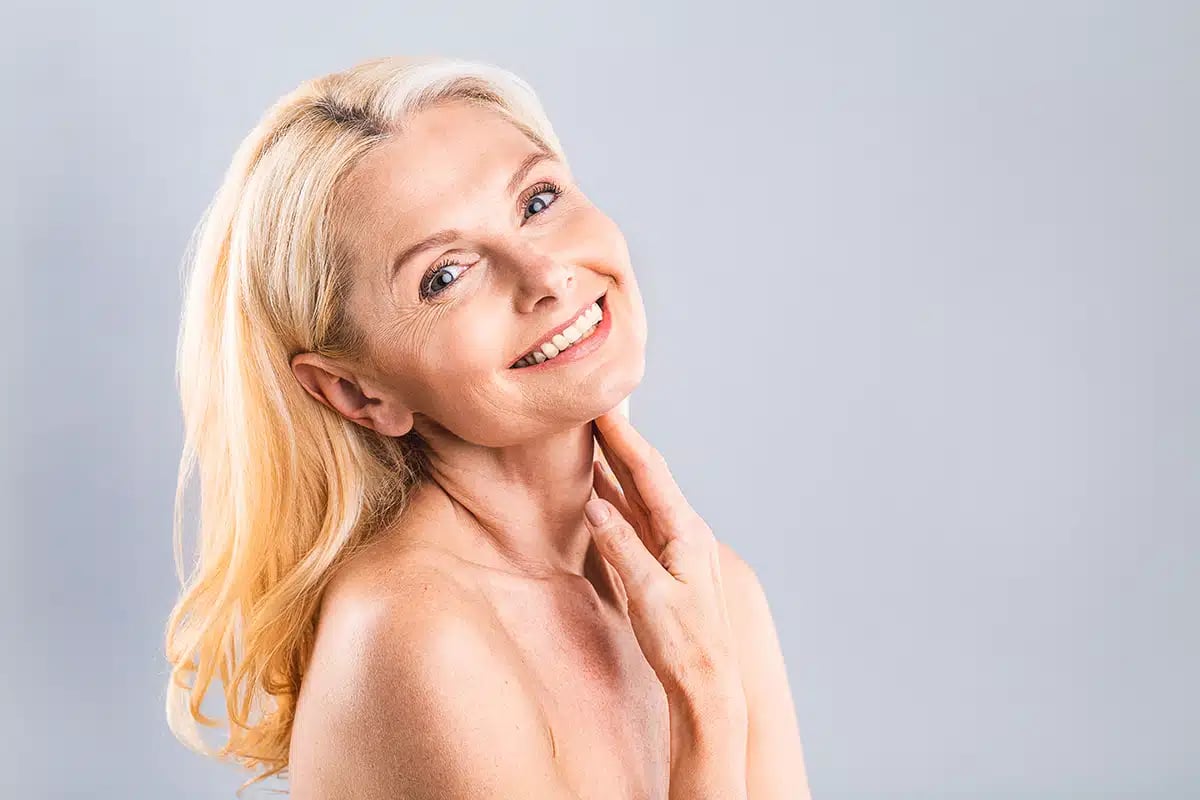 Close up portrait of a beautiful, attractive, charming, naked, nude woman touching her perfect skin