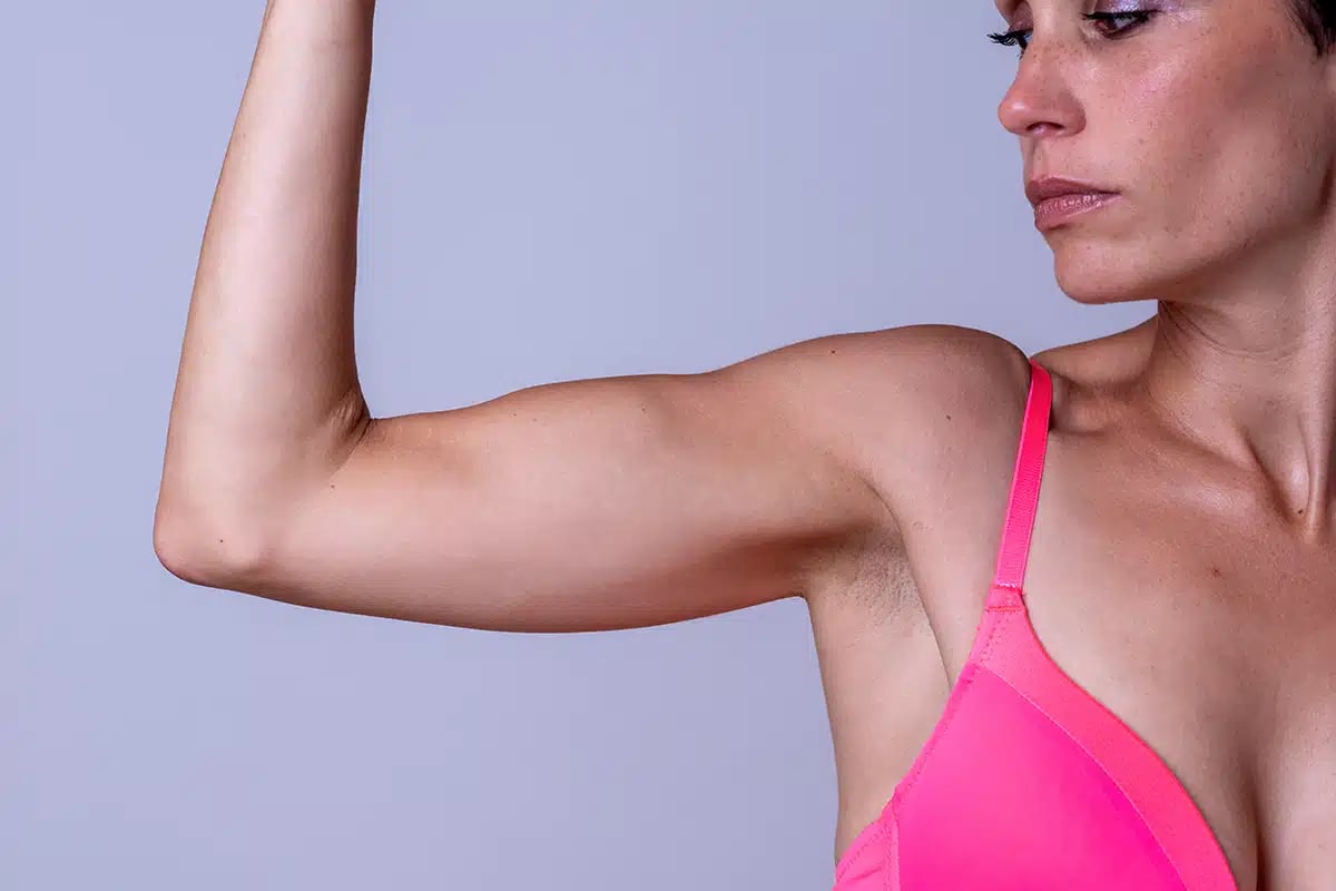 Serious woman in pink bra holding up arm