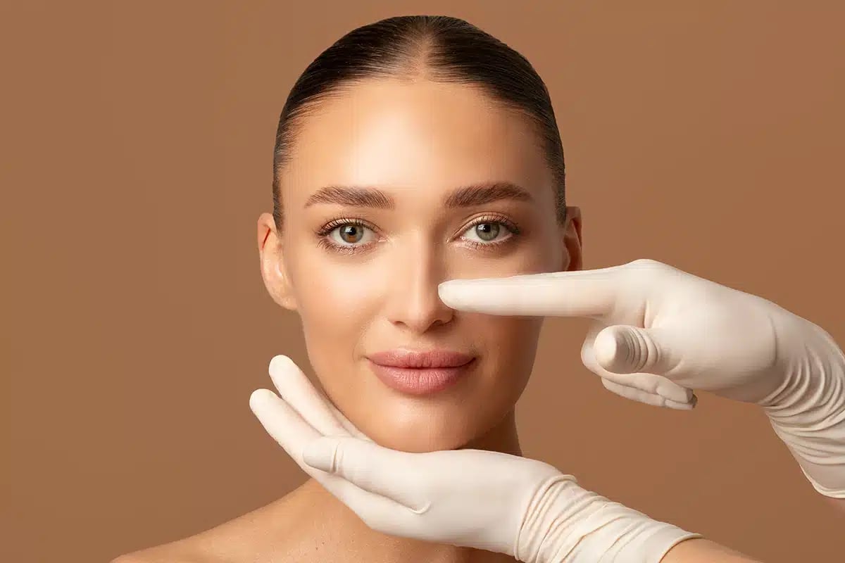 Surgeon hands touching woman nose, examining lady before plastic surgery