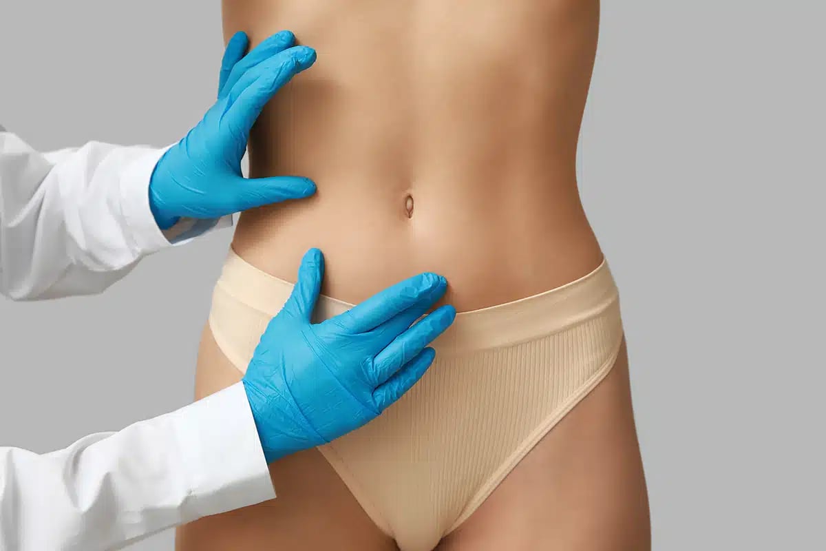 Surgeon examining abdomen for tummy tuck consultation
