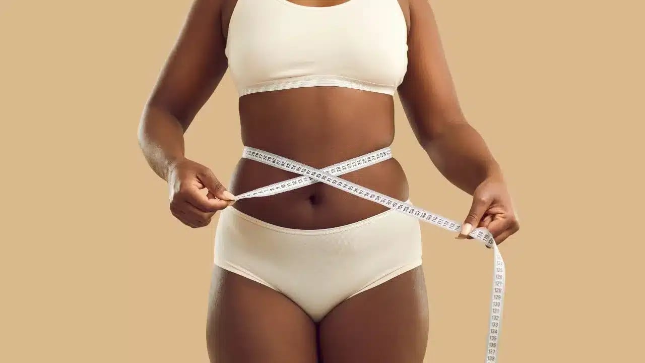 Patient measuring waist before tummy tuck or weight loss